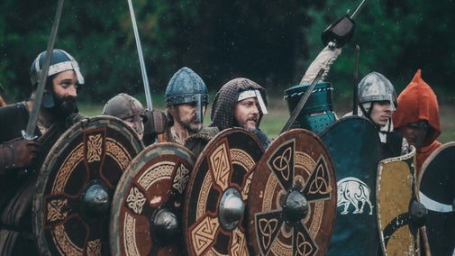 Historical re-enactors carrying decorated shields and weapons during a Battle of Crogen re-enactment.